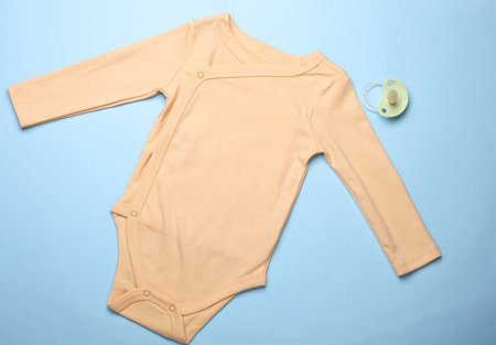 Newborn romper and pacifier on blue background