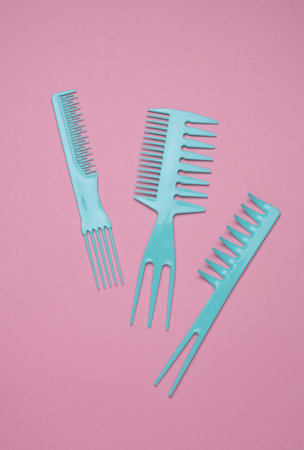 Set of blue plastic combs on pink background.