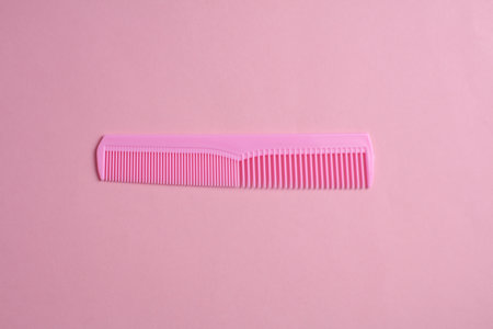 Plastic comb on pink background. Hair care