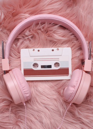 Retro 80s audio cassette and stereo headphones on fuzzy fluffy pink background. Top viewの写真素材
