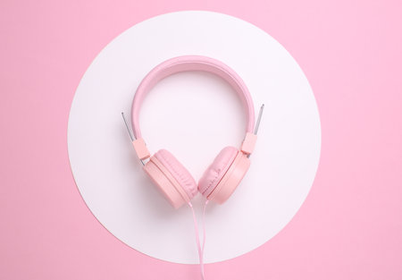 Stereo headphones on a pink background with white roundの写真素材
