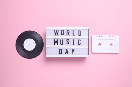World music day text in light box and retro 80s audio cassette, vinyl record on pink background....