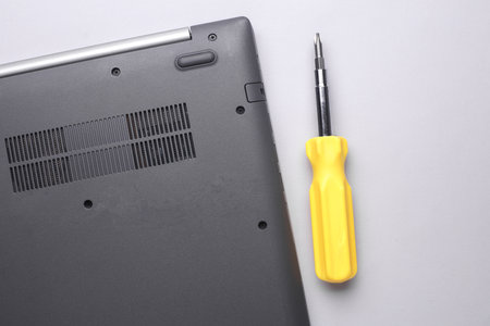 Computer repair. Laptop with screwdriver on gray background