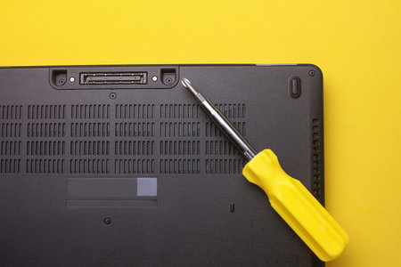 Computer repair. Laptop with screwdriver on yellow backgroundの写真素材
