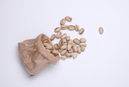 Pistachios in a paper bag on a white background