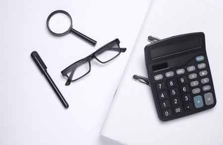 Black classic calculator with stationery on white background. Office accessories. Top view. Flat lay. Working spaceの写真素材
