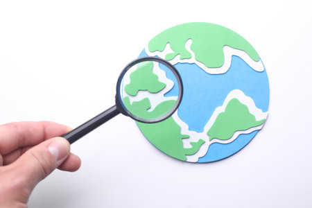 Hand with magnifying glass examines globeの写真素材