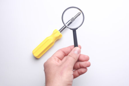 Hand with a magnifying glass examines screwdriverの写真素材