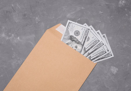 Envelope with hundred dollar bills on concrete background. Paying taxesの写真素材