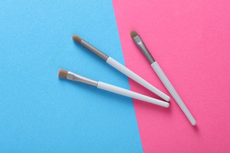 Set of makeup brushes on pink blue background
