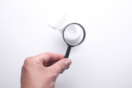 Hand with a magnifying glass examines toy toiletの写真素材