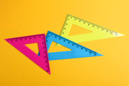 Rulers triangles on yellow background. Top view