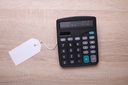 Black classic calculator with price tag on table. Top view