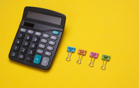 Calculator with smiling binders on yellow backgroundの写真素材