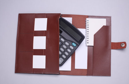 calculator and note book in brown leather briefcase on white background