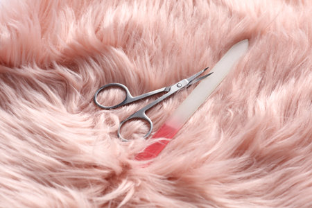 Manicure scissors and nail file on pink fur background.の写真素材