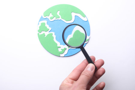 Hand with magnifying glass examines globeの写真素材