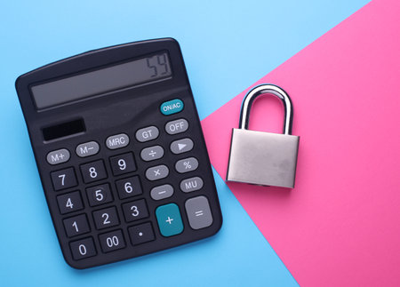 Black classic calculator and metal lock card on pink blue background. Top view