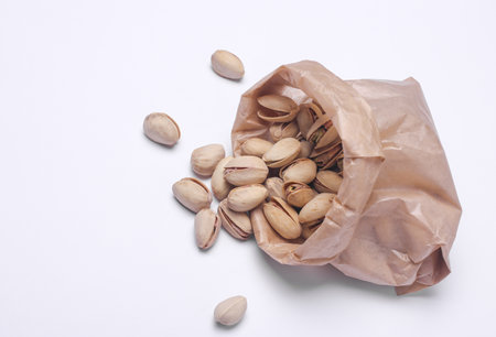 Pistachios in a paper bag on a white background
