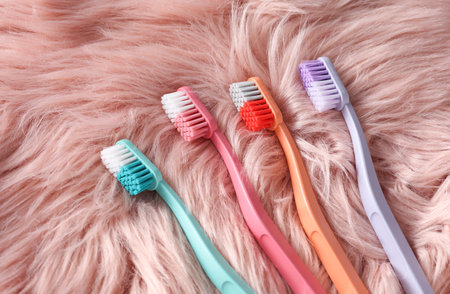 Plastic toothbrushes on pink fur background.