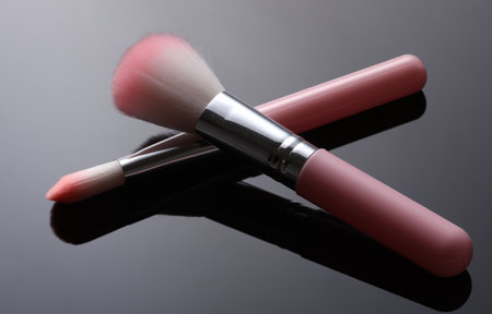 Pink makeup brushes on black background