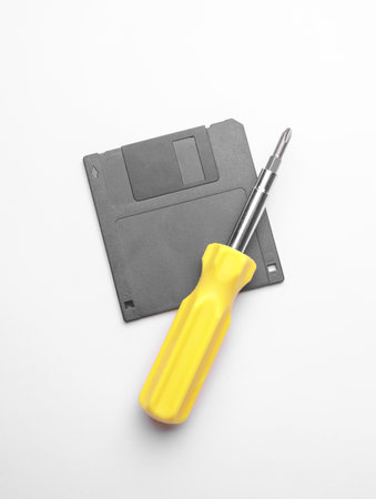 Floppy disk and screwdriver on white background