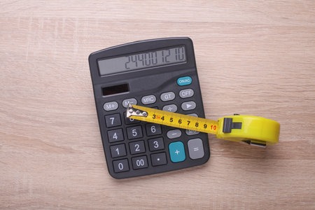 Calculator with construction tape measure on table