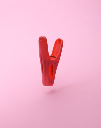 Plastic clothespin floating on pink background