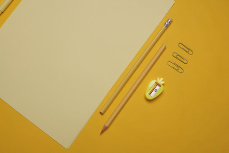 Sheets of paper with school stationery on yellow background. Monochrome photography. Flat lay. Creative layoutの写真素材