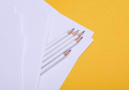Pencils with white blank sheets of paper on yellow backgroundの写真素材