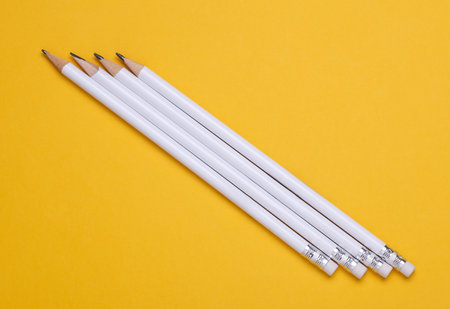 White wooden pencils with erasers on yellow background. Mockup for designの写真素材