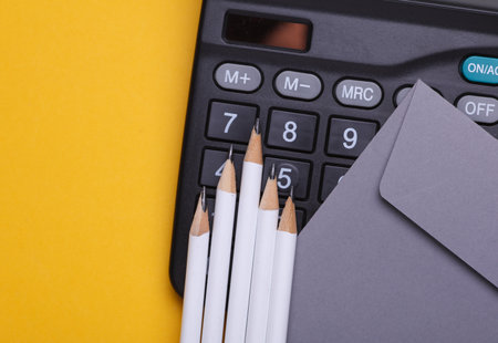 Envelope with calculator, pencils on yellow background. Business concept