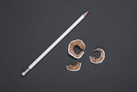 White sharpened pencil and shavings on dark gray backgroundの写真素材