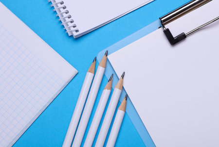 Workspace with pencils, clipboard and notebook. Flat lay