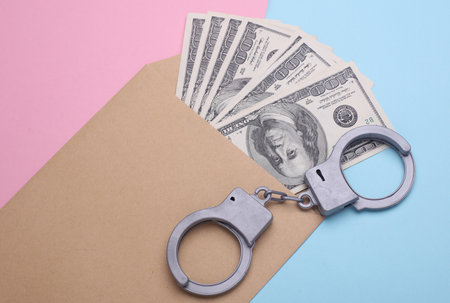 Envelope with money and handcuffs on a pink blue background. Corruption, crimeの写真素材