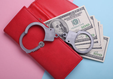 Dollar bills in purse and handcuffs on pink blue background. Corruption, crime