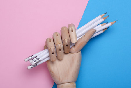 Wooden hand holding pencils on blue pink backgroundの写真素材