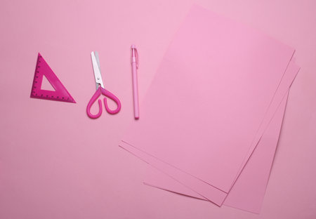 Pink sheets of paper with school stationery on pink background. Monochrome photography. Flat lay