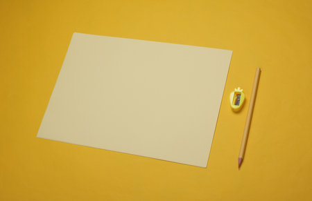 Sheets of paper with pencil and sharpener on yellow backgroundの写真素材