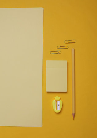 Sheets of paper with school stationery on yellow background. Monochrome photography. Flat lay....