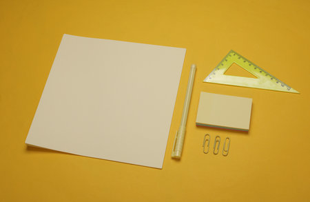 Sheets of paper with school stationery on yellow background. Monochrome photography. Flat lay. Creative layoutの写真素材
