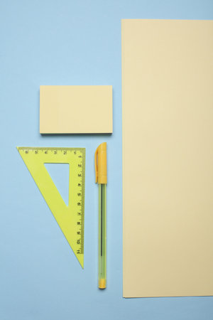 Yellow sheets of paper and school stationery on a blue background. Creative layout