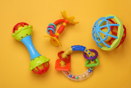 Rattles toys for newborn on yellow background