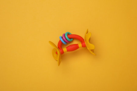 Rattle toy for newborn on yellow background