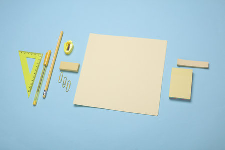 Yellow sheets of paper and school stationery on a blue background. Creative layout