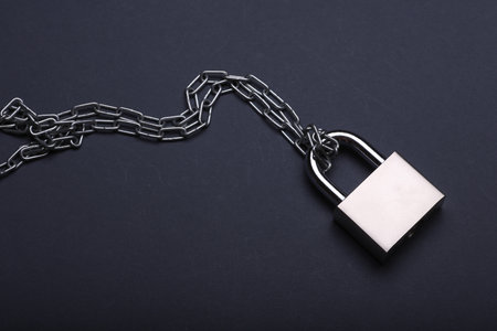 Metal chain with lock on dark backgroundの写真素材