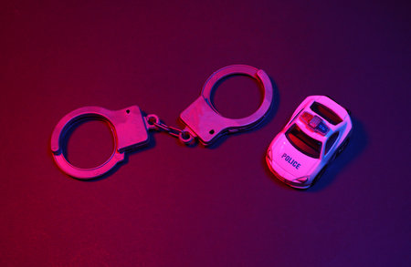 Toy handcuffs and police car in red blue neon light