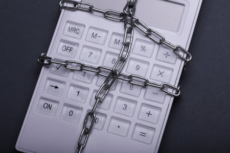 Calculator wrapped in steel chain on dark backgroundの写真素材