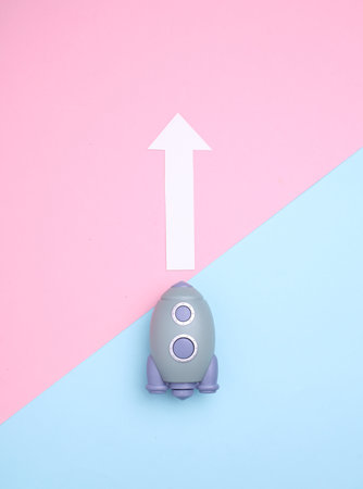 Toy space shuttle and growth arrow on blue pink background. Startup ideaの写真素材