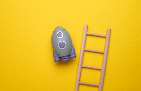 Toy space shuttle and stairs on yellow background. Startup ideaの写真素材